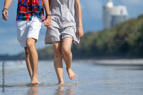 Selective focus of young adult couple men and women enjoying romantic holiday travel and walking together on the island sea beach in hot summer time.