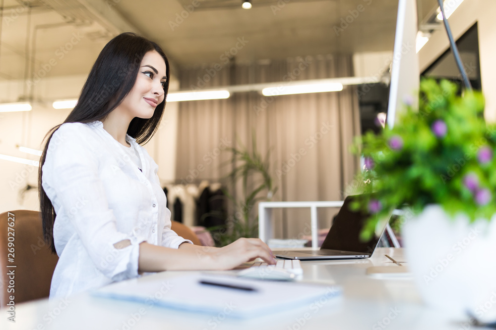 Portrait of a businesswoman sitting on her workplace in the office, typing, looking at pc screen. Portrait of a businesswoman sitting on her workplace in the office, typing, looking at pc screen.