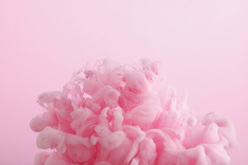Close up view of pink paint swirls in water isolated on pink