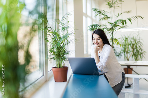 Foto Young pretty woman working at lap top in the office.