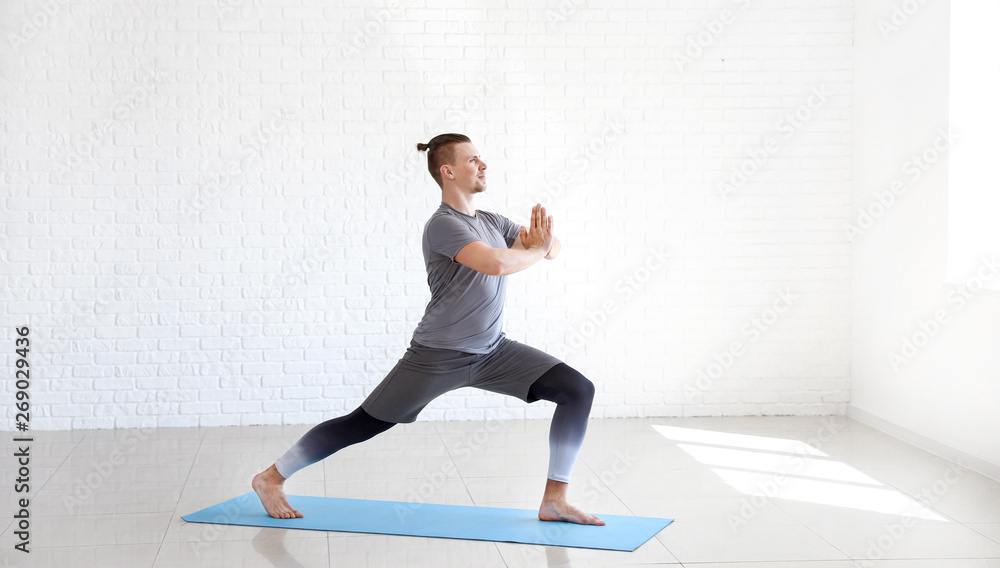 Sporty man practicing yoga in gym