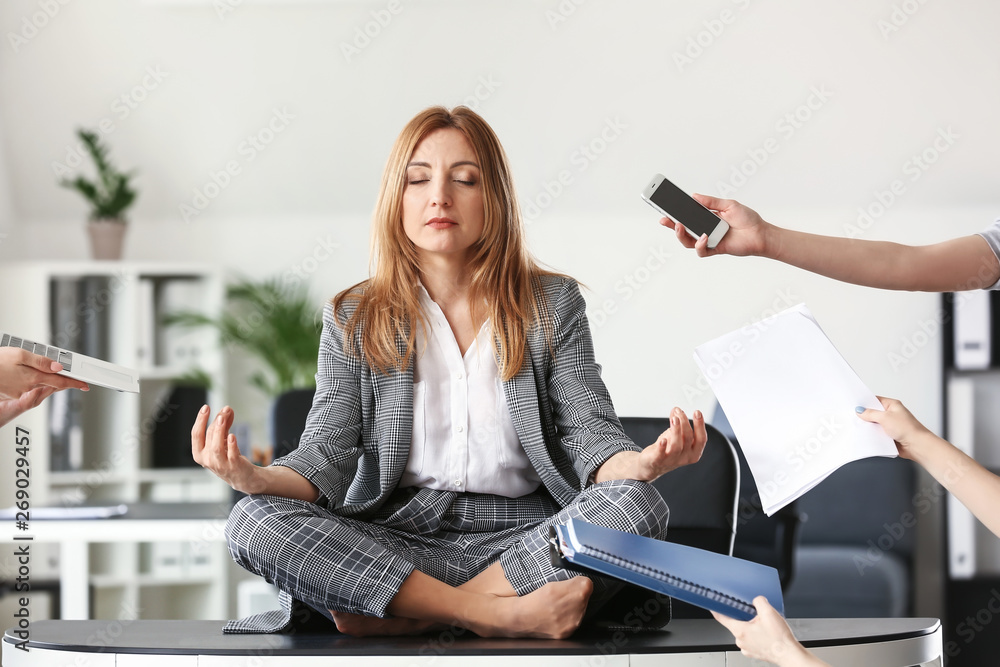 Mature businesswoman with a lot of work meditating in office - obrazy, fototapety, plakaty 
