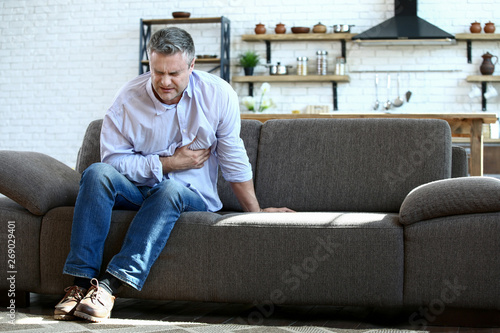 Handsome mature man having heart attack at home photo