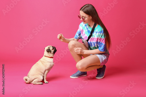 Teenage girl with cute pug dog on color background photo