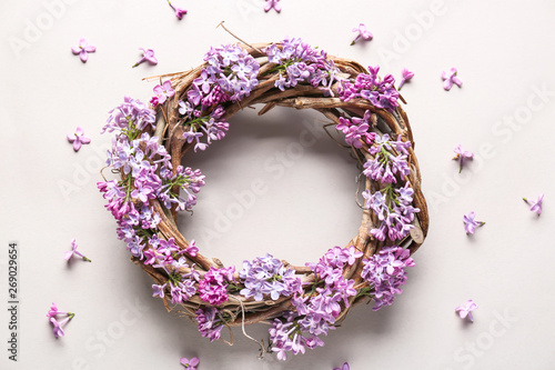 Wreath with beautiful lilac flowers on light background