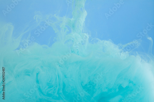 Close up view of turquoise watercolor swirls isolated on blue