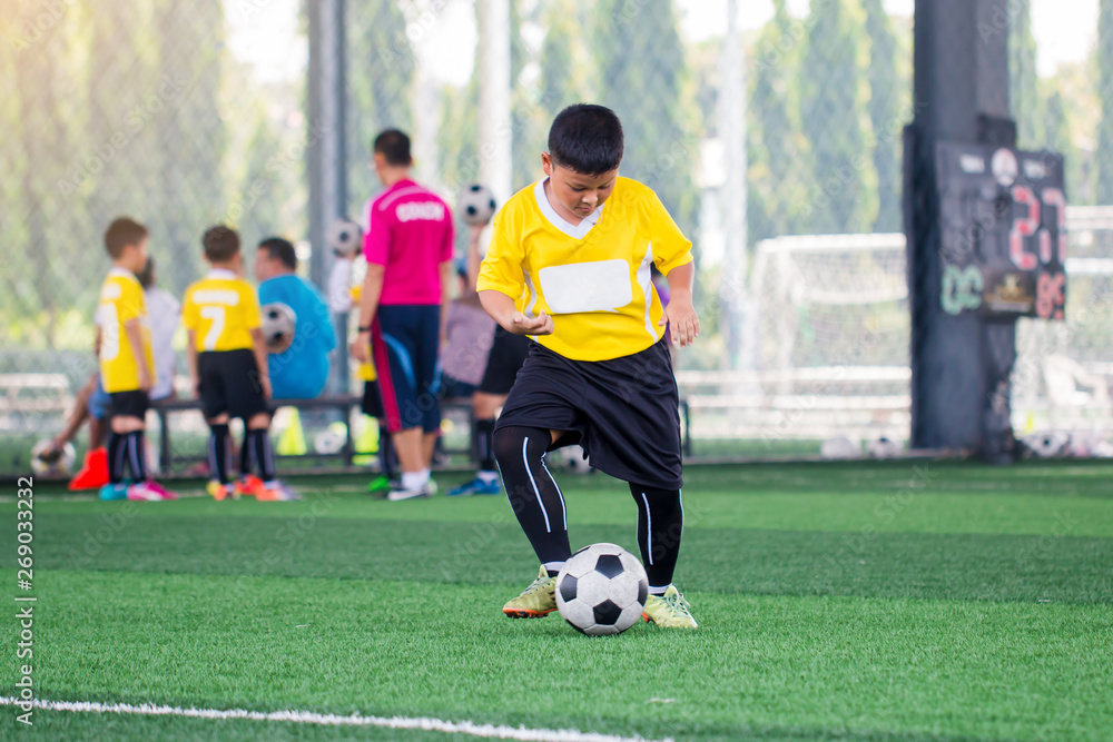 blurry ball with Asian kid soccer player speed run to shoot ball to goal on artificial turf. blurry ball with Asian kid soccer player speed run to shoot ball to goal on artificial turf.