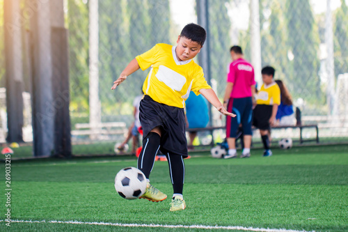blurry ball with Asian kid soccer player speed run to shoot ball to goal on artificial turf. © Koonsiri