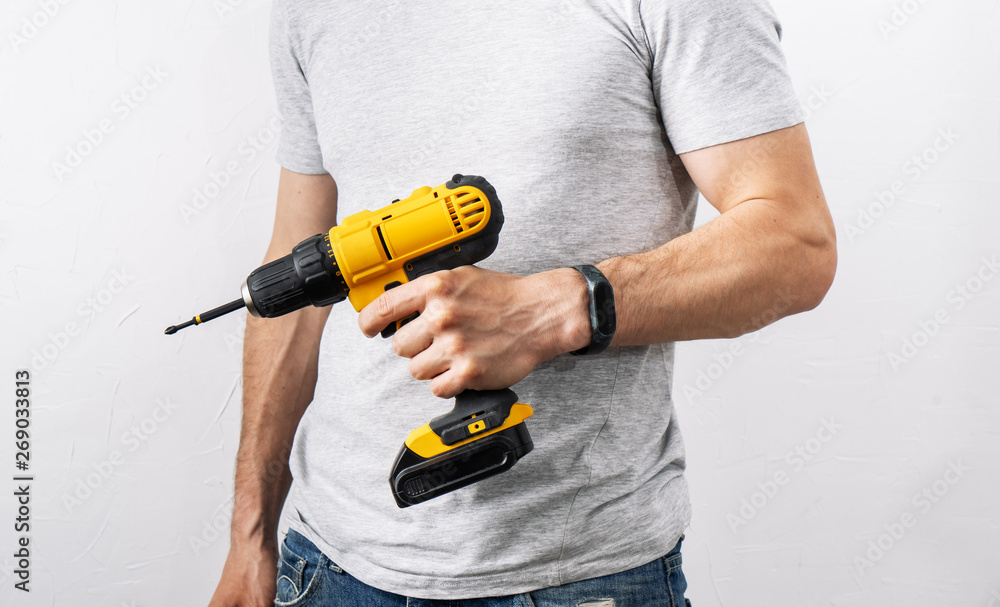 Construction: A man is holding a yellow electric screwdriver.