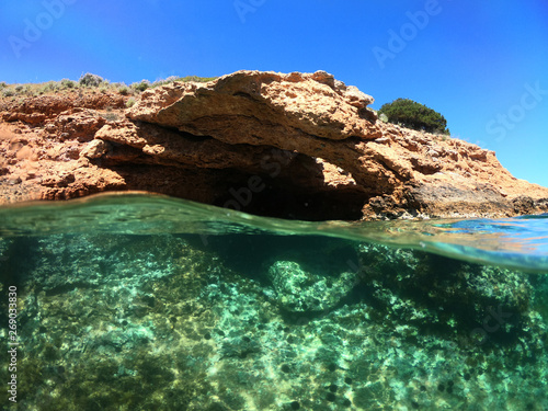 Underwater photo of tropical cave with emerald clear sea and coral reef