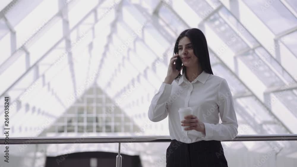nice manager girl is calling and holding cup in business centre during break nice manager girl is calling and holding cup in business centre during break