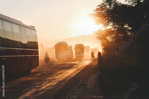 Fototapeta Hue,Vietnam - SEP 2015: Dusty Vietnam street, air pollution, road maintenance wokers come back home after work at sunset