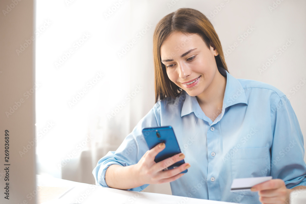 Online payment. Smiling girl using phone pays by credit card. Online payment. Smiling girl using phone pays by credit card.