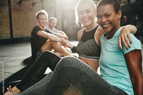 Two smiling women sitting in a gym after working out photo