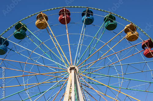 Beautiful ferris wheel. Bottom-up view. Attraction on the background of blue clear sky
