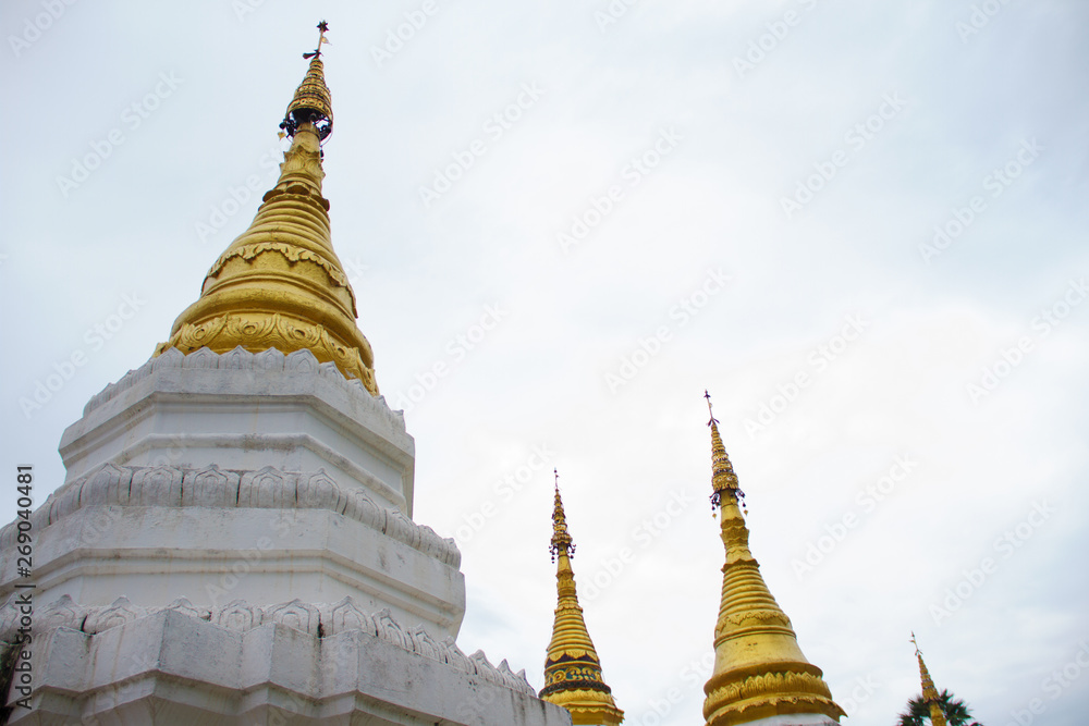 Many golden pagodas on the courtyard of temple in northern thailand, with blue sky background.