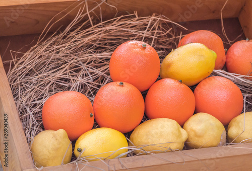 ripe yellow lemons and orange oranges in a wooden box