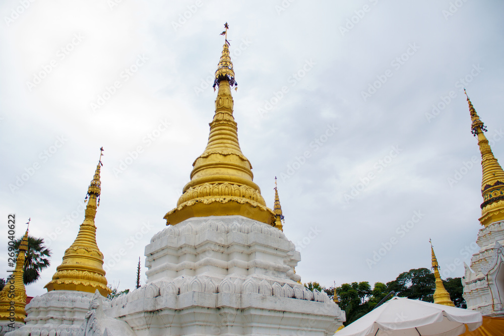 Many golden pagodas on the courtyard of temple in northern thailand, with blue sky background.