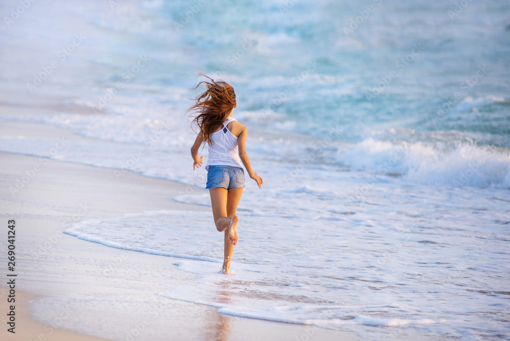 Fototapeta premium Young girl running along the beach in Dubai