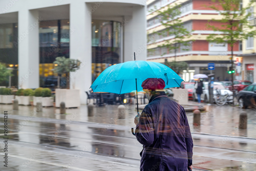 Woman walking by with an umbrella during the rain