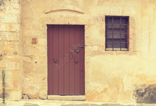 The background old beige stony wall with door and a window