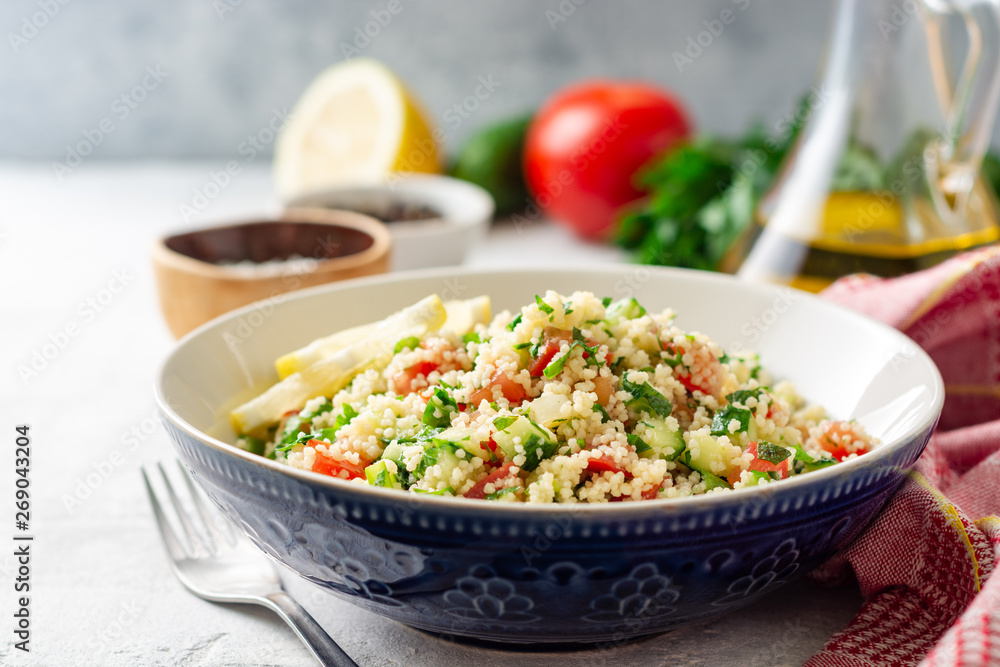 Traditional Arabic Salad Tabbouleh with couscous, vegetables and greens on concrete background. Selective focus. Traditional Arabic Salad Tabbouleh with couscous, vegetables and greens on concrete background. Selective focus.