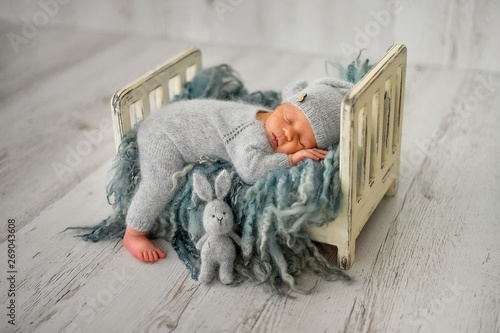 A newborn baby boy is sleeping on a little cot in the first days of life 