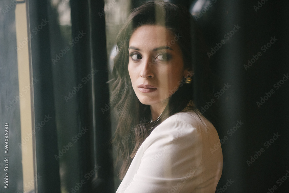 Fototapeta premium Young brunette woman posing in a suit by the window