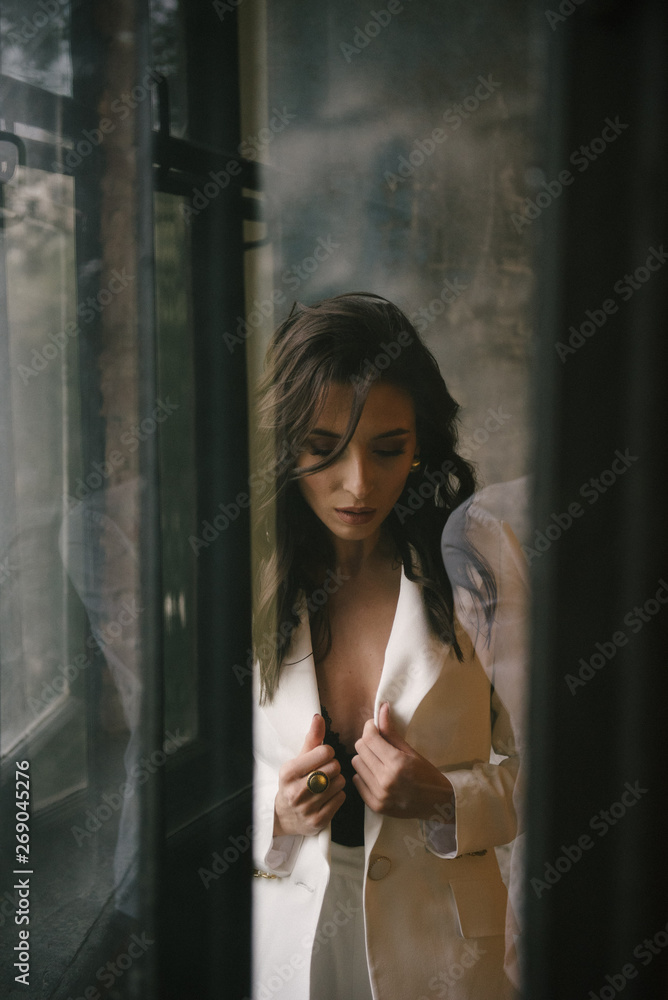 Young brunette woman posing in a suit by the window Young brunette woman posing in a suit by the window