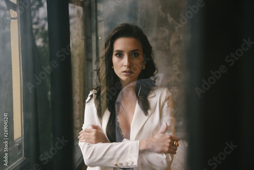 Young brunette woman posing in a suit by the window