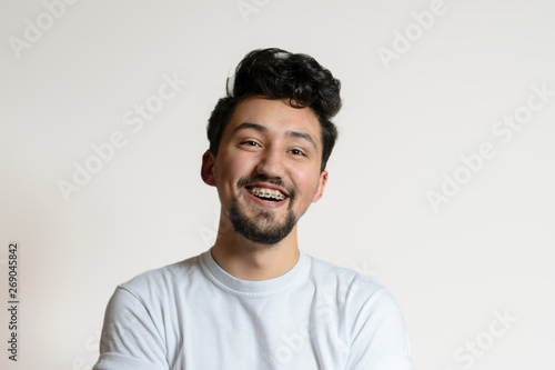 Portrait of a young man with braces smiling and laughing. A happy young man with braces on a white background