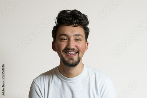 Portrait of a young man with braces smiling and laughing. A happy young man with braces on a white background © Ungureanu