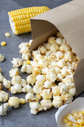 Popcorn in paper cup pouring on table.
