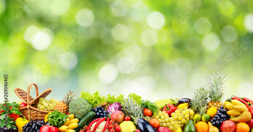 Fruits, vegetables, berries on green natural blurred background.