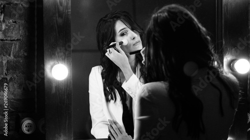 Young brunette woman looks at herself in the mirror