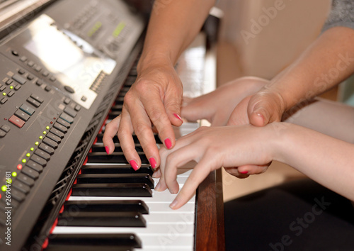 Learning to play the piano. Close-up on female and children's hands and keyboard. 