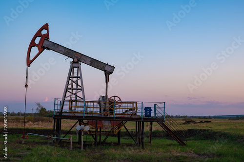 Oil and gas production equipment running at sunset