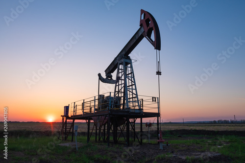 Oil and gas production equipment running at sunset