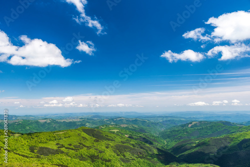 Panoramic view of idyllic mountain scenery with fresh green meadows and forests on a beautiful sunny day in springtime