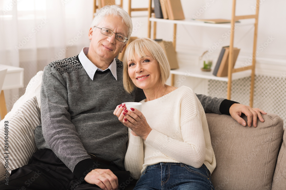 Loving Mature Couple Resting On Sofa And Looking At Camera Loving Mature Couple Resting On Sofa And Looking At Camera