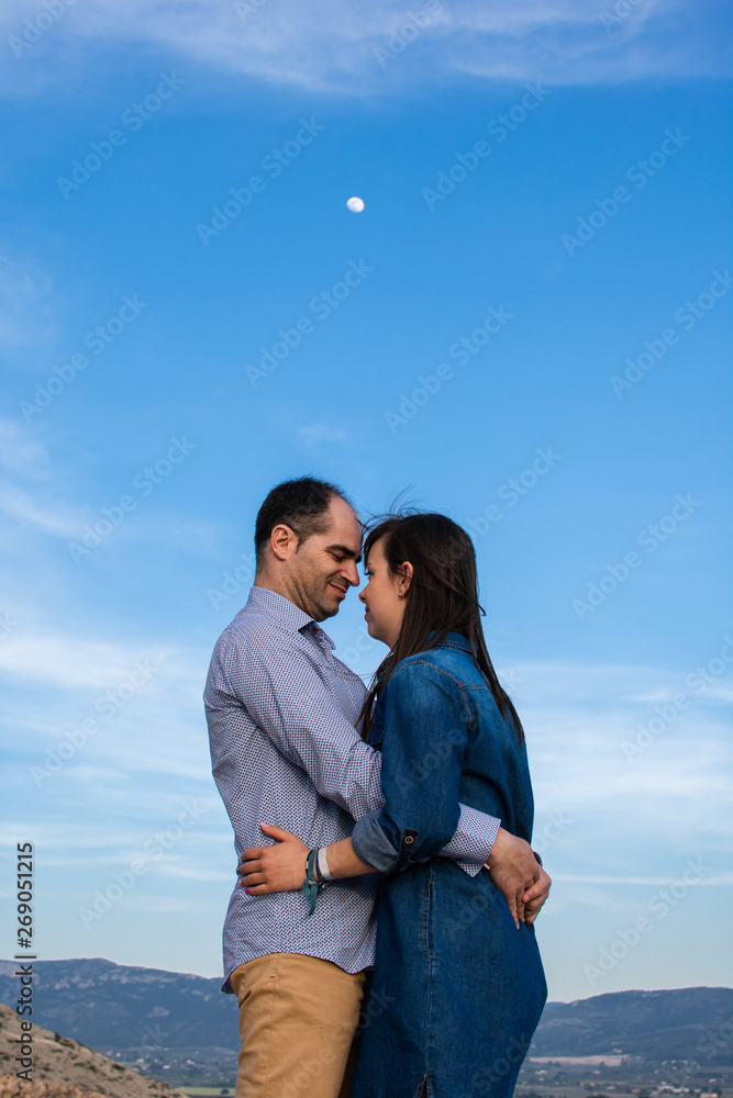 Young couple embraced with the moon in the background
