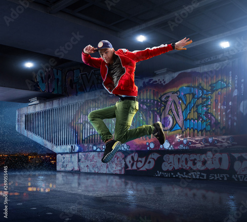 Male Hip Hop Dancer. Beautiful man dancing at night on the background of graffiti wall