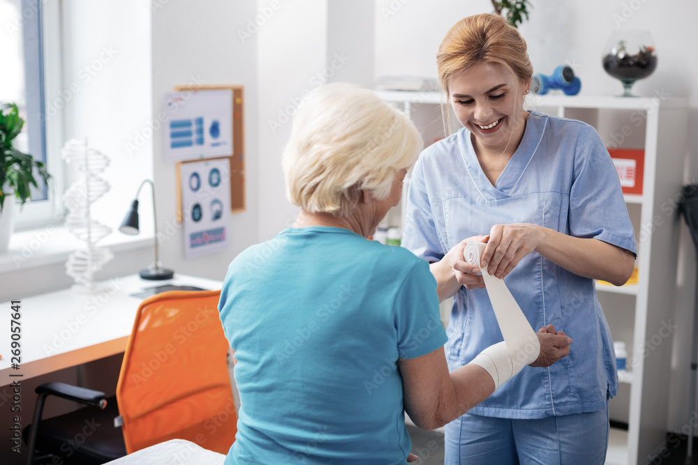 Fototapeta premium Delighted blonde woman talking with her aged patient