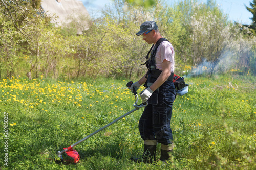 A man mows the grass on the lawn mowers. Overalls and tools.