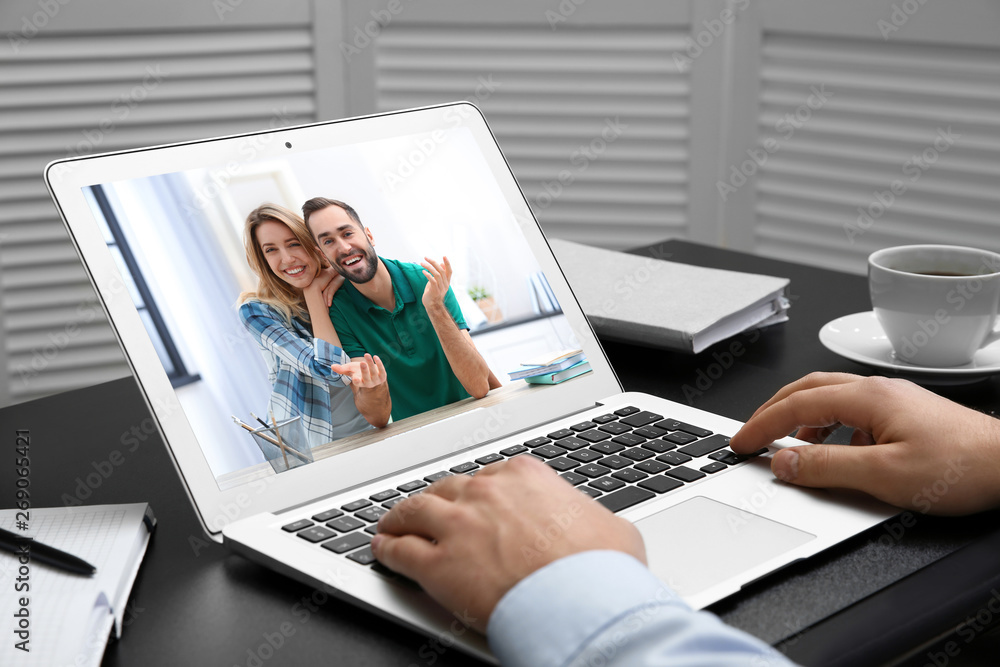 Man using laptop for conversation via video chat at table, closeup Man using laptop for conversation via video chat at table, closeup