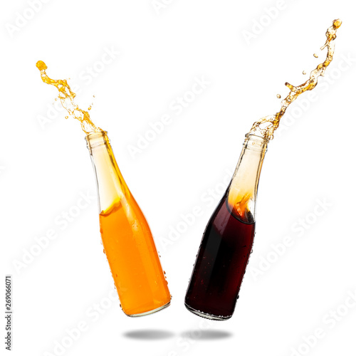Fotografie Cola and orange soda splashing out of glass bottle isolated on white background