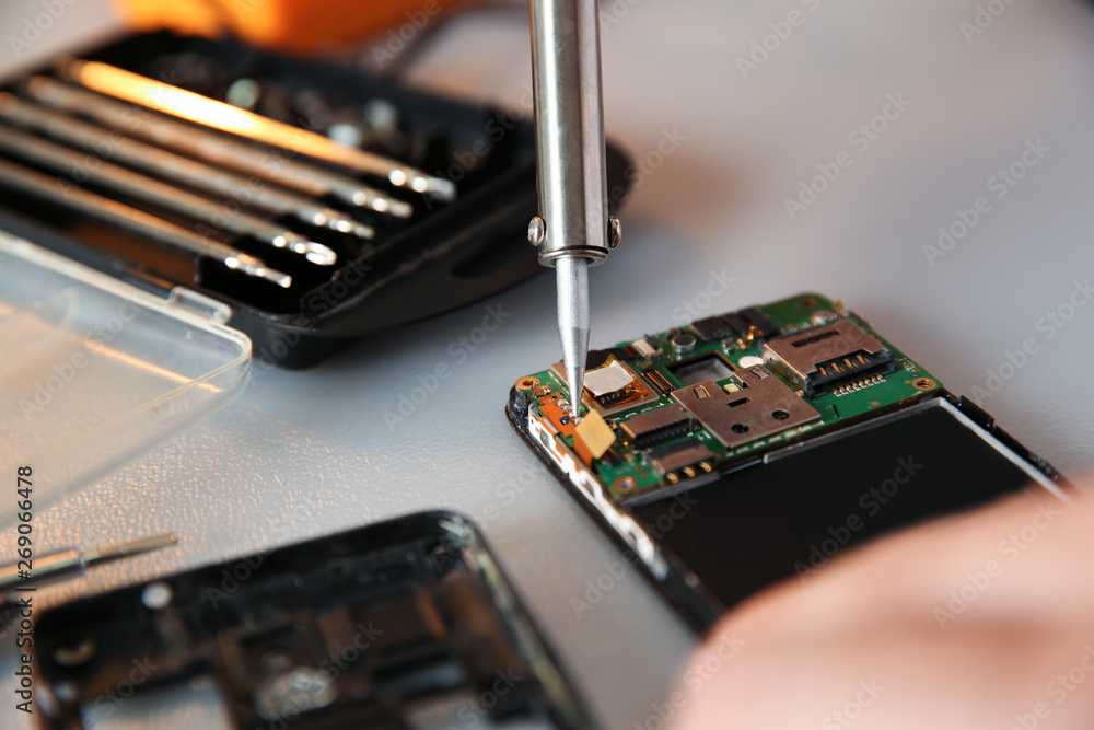 Technician repairing mobile phone at table, closeup Technician repairing mobile phone at table, closeup
