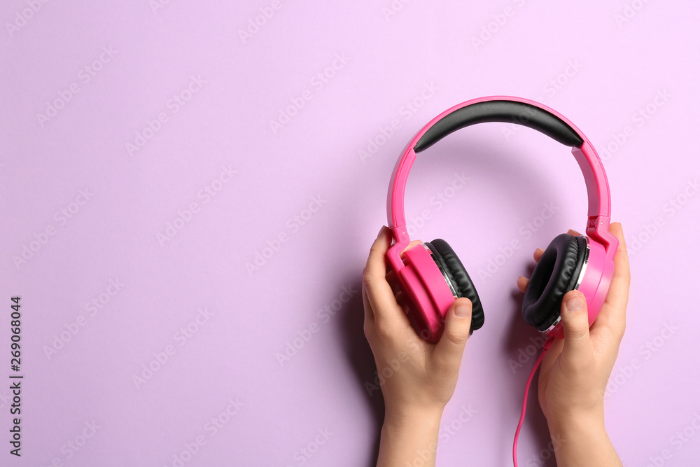 Woman holding stylish headphones on color background, closeup. Space for text Woman holding stylish headphones on color background, closeup. Space for text