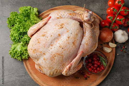 Wooden board with raw spiced turkey and ingredients on grey background, top view photo