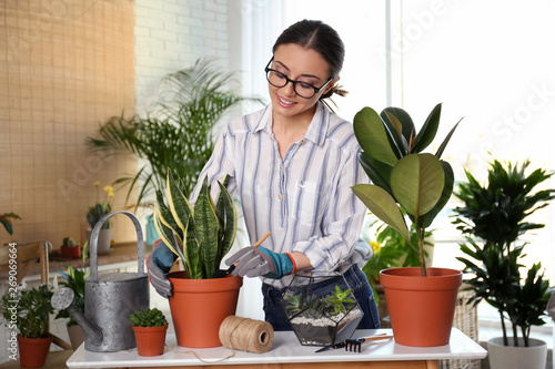 Young woman taking care of potted plants at home